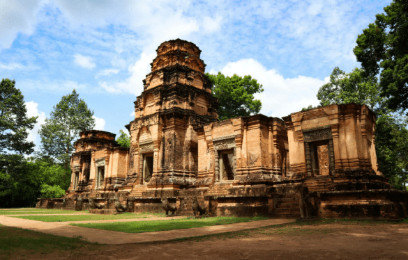 Ancien temple en pierre entouré de forêt tropicale, architecture d’Asie du Sud-Est sous un ciel bleu.