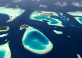 Vue aérienne spectaculaire des atolls des Maldives avec leurs lagons turquoise, leurs plages de sable blanc et l’océan Indien d’un bleu profond — une destination de rêve pour les vacances au soleil.