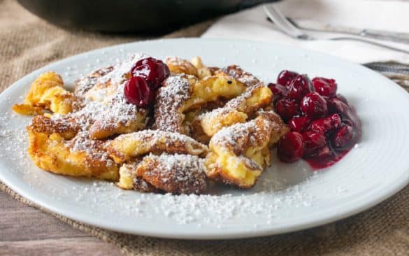 Assiette de Kaiserschmarrn, crêpe épaisse autrichienne saupoudrée de sucre glace, servie avec des cerises sur les marchés de Noël de Vienne.