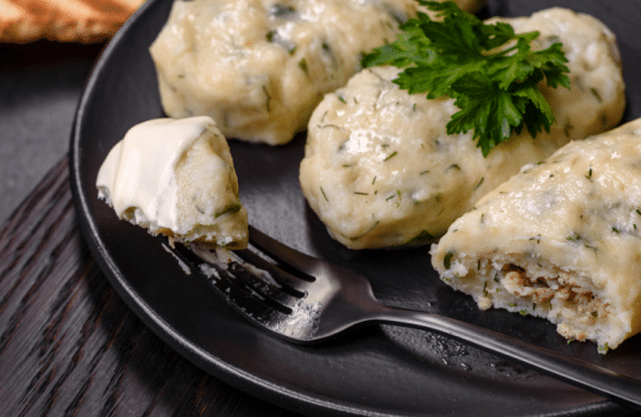 Assiette de Cepelinai, quenelles de pommes de terre farcies à la viande, servies avec crème et aneth, spécialité lituanienne typique de Vilnius.