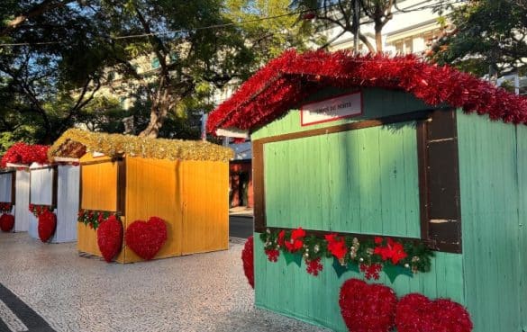 Chalets colorés décorés pour le marché de Noël de Funchal à Madère, sous un ciel ensoleillé.
