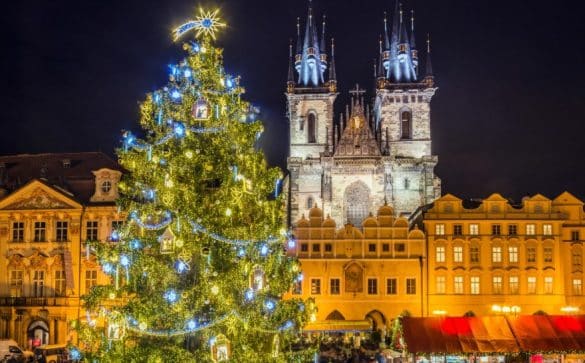 Marché de Noël à Prague sur la place de la Vieille-Ville, avec un grand sapin illuminé et l’église Notre-Dame du Týn en arrière-plan.