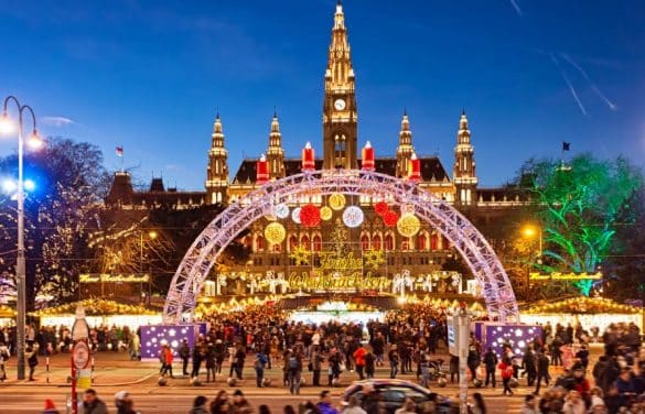Marché de Noël à Vienne sur la Rathausplatz, avec l’hôtel de ville illuminé et la grande arche décorée de lumières festives.