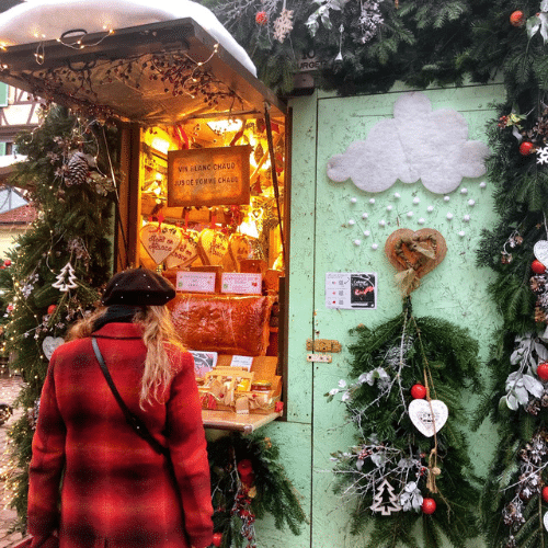Visiteuse devant un chalet décoré sur le marché de Noël d’Obernai en Alsace, France.