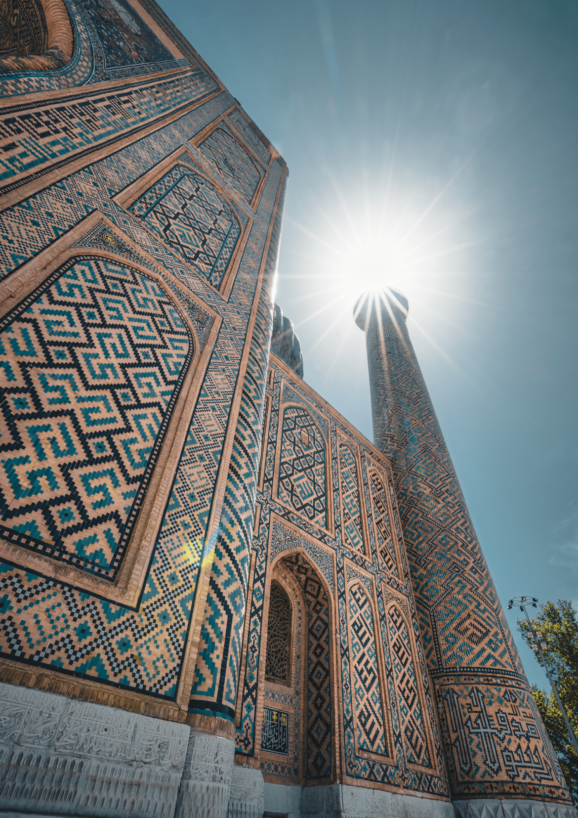 Minaret et mosaïques du Registan à Samarcande en Ouzbékistan Vue en contre-plongée d’un minaret et des mosaïques de la place du Registan à Samarcande en Ouzbékistan sous le soleil.