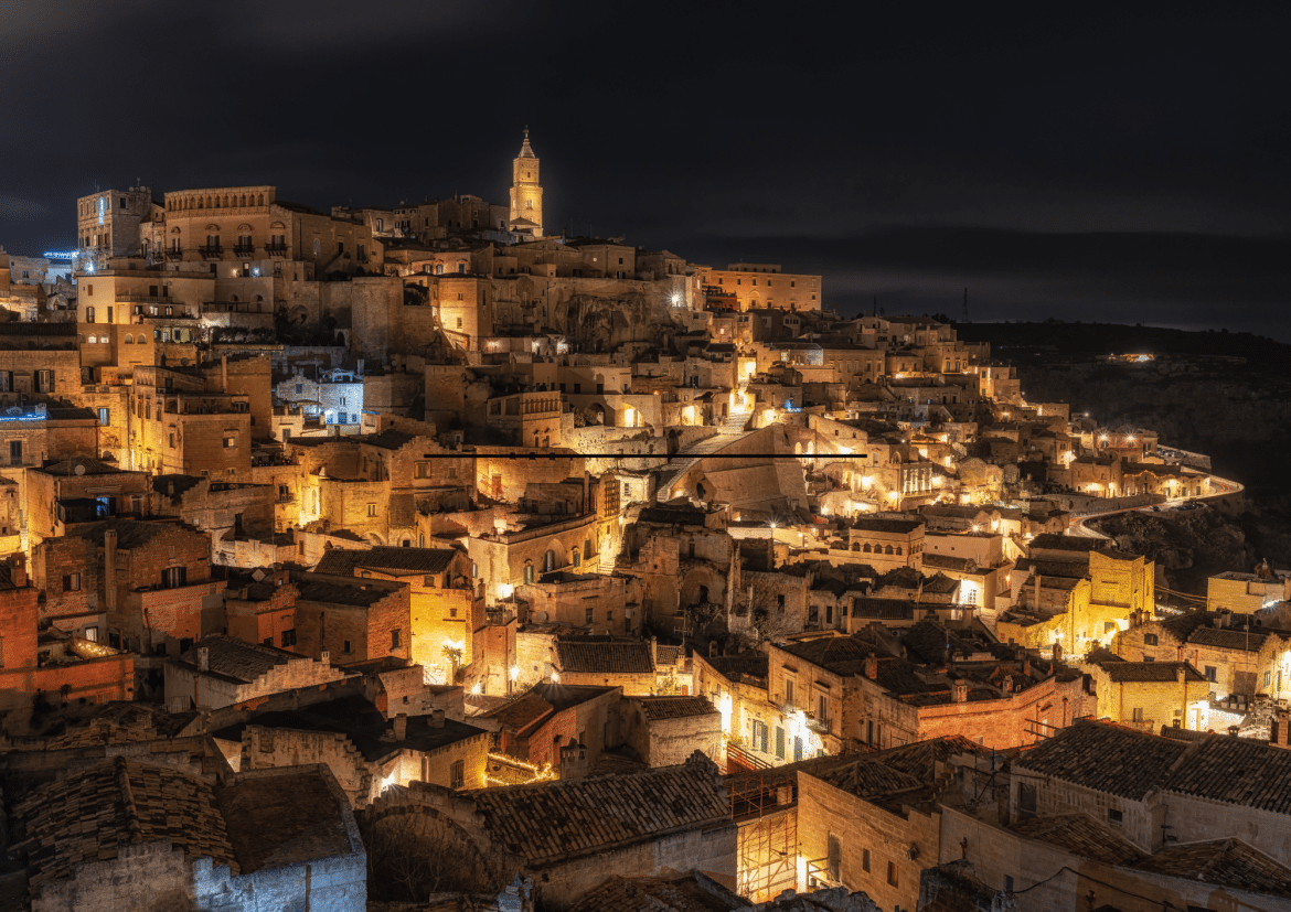 Sassi di Matera de nuit : cité troglodytique illuminée en Italie Vue nocturne des Sassi di Matera en Italie avec habitations troglodytiques éclairées et ambiance chaleureuse