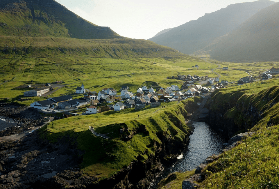 Village traditionnel au cœur des montagnes verdoyantes lors d’un voyage aux îles Féroé